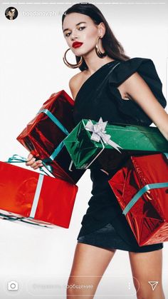 a woman in a black dress holding many presents