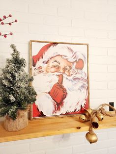 there is a christmas painting on the mantle next to a potted tree and bells