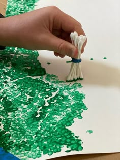 a person is painting with green and white paint