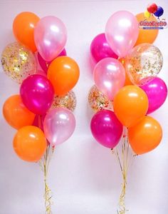 two bunches of balloons with gold and pink confetti on them against a white wall