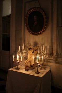 a table topped with lots of candles next to a painting