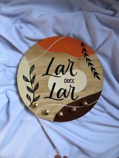 a wooden sign that says lar doce lar on top of a white sheet