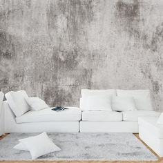 a white couch sitting on top of a wooden floor in front of a cement wall