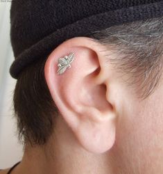 a close up of a person with a hat on their head wearing a pair of ear piercings