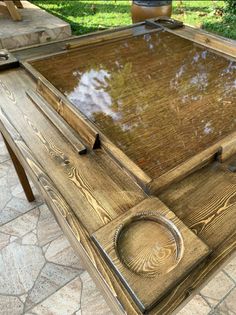 a wooden table with glass top sitting on a patio