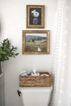 a white toilet sitting in a bathroom next to a painting on the wall above it