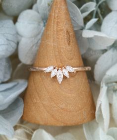 a close up of a ring on top of a piece of wood with flowers in the background