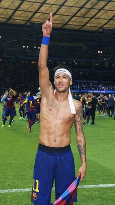 a shirtless soccer player waves to the crowd as he holds his hand up in victory