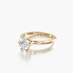 a yellow gold engagement ring with a single diamond in the center, on a white background