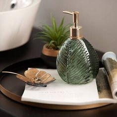 a soap dispenser sitting on top of a table next to a plant