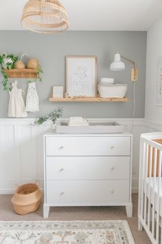 a baby's nursery room with white furniture and neutral accessories on the shelves, including a crib