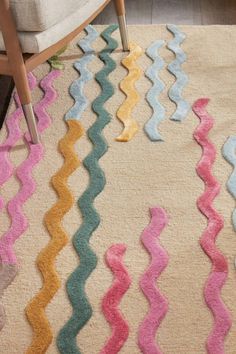 an area rug with different colored wavy lines on the floor in front of a chair