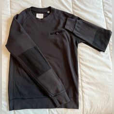 a black shirt laying on top of a bed