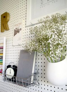 there is a vase with flowers and a clock on the wall next to some books