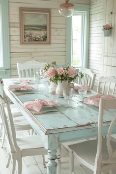 a dining room table with white chairs and pink napkins on the placemates