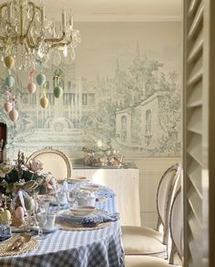 a dining room table set with place settings and flowers in vases on the table