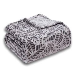 four blankets stacked on top of each other in grey and white leaves print, with one blanket folded over the edge