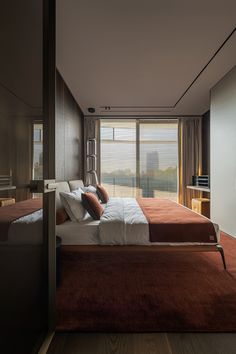 a large bed sitting in the middle of a bedroom next to a tall glass window