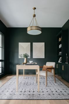 a dining room with dark green walls and white chairs, two paintings on the wall