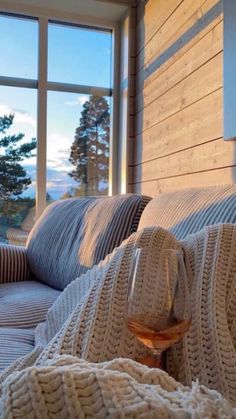 a glass of wine sitting on top of a bed in front of a large window