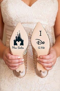 a bride holding her wedding shoes with the disney castle on them, which reads i do