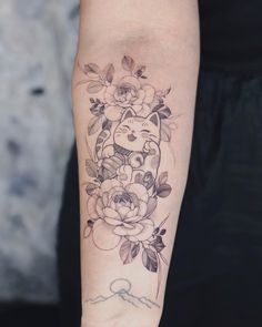 a woman's arm with a cat and flowers tattoo on it