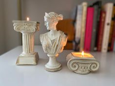 there are two candles that have been placed next to each other on a table with books in the background