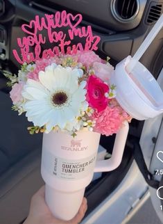 a person holding a coffee mug with flowers in it