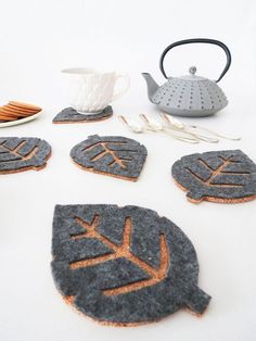 the coasters are made out of felt and have leaves on them, along with a teapot