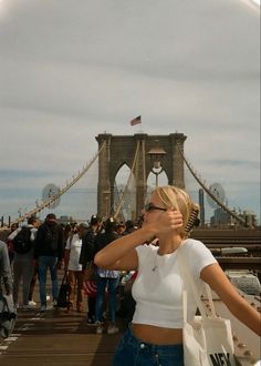 a woman is standing on a bridge and looking at the sky with her hand in her mouth