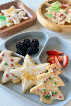 three trays filled with decorated cookies and fruit