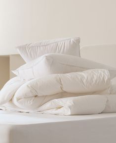 an unmade bed with white sheets and pillows