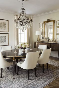 an elegant dining room with chandelier and white chairs in front of the table