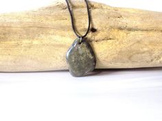 This pendant is made with a coastal stone, either ocean or river. The stone is not tumbled or shaped but is in its natural form, except for the drilled hole. Therefore, the stone/rock will have its natural "imperfections" just as nature made it. This adds character and uniqueness to the piece. They make a perfect gift for rockhounds, yoga\ Zen lovers, surfers or just anyone who loves the beauty of nature. This pendant is gray with unique markings on the front.  Then the entire piece is coated with a high gloss shellac to give it a nice sheen and protect the design. Pendant has a metal split ring and hangs on an adjustable wax cotton cord with pull apart clasp.  To adjust the length of the cord: 1. pull  open the clasp; 2. push knot through clasp end on both sides; 3. tie a new knot at the Rock Pendant, Boho Hippie Style, Natural Form, Casual Jewelry, Natural Rock, Pull Apart, Rock Hounding, Jewelry Boho, Natural Forms