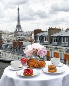 the table is set with pastries and coffee on it, overlooking the eiffel tower