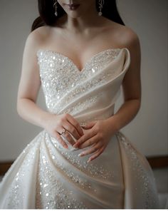 a woman in a wedding dress holding her hands together