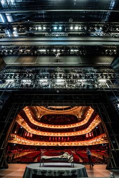 an auditorium with lots of lights on the ceiling and people standing in front of it