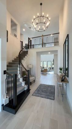 a large foyer with stairs leading up to the second floor and a chandelier hanging from the ceiling