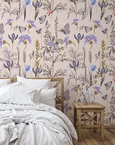 a bed sitting next to a pink wallpaper with flowers and butterflies on the walls