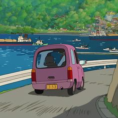 a pink car driving down a road next to a body of water