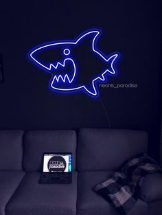 a blue neon shark is on the wall next to a couch