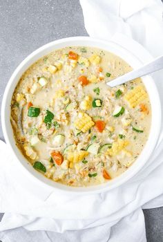 a white bowl filled with soup on top of a table next to a napkin and spoon