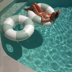 a woman laying on an inflatable raft next to a swimming pool with another floating object