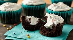 chocolate cupcakes with white frosting and sprinkles on a napkin