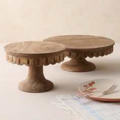 two wooden cake stands sitting on top of a table next to a plate and fork