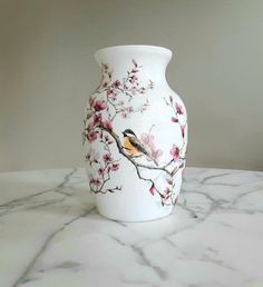 a white vase sitting on top of a marble table covered in pink and yellow flowers