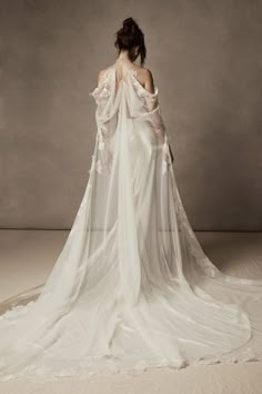 a woman in a white wedding dress with an open back and long veil on her shoulder