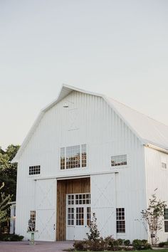 a large white barn with two doors and windows