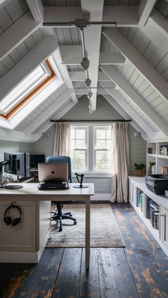 an attic home office with wood floors and white walls, along with a desk in the center