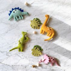 small felt dinosaurs are arranged on a marble surface